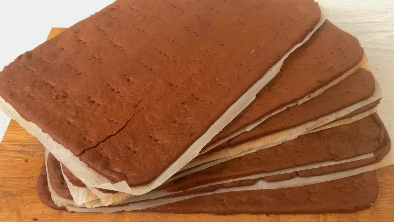 Шоколадно-медові коржі, спечені тонкими пластами й охолоджені на пергаменті