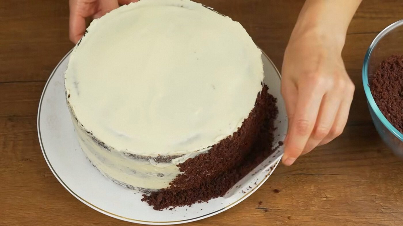 Подрібніть зрізану з бісквіта верхівку блендером та покрийте крихтою боки торта